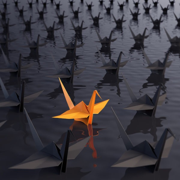 orange coloured origami swan stands out from the other black ones