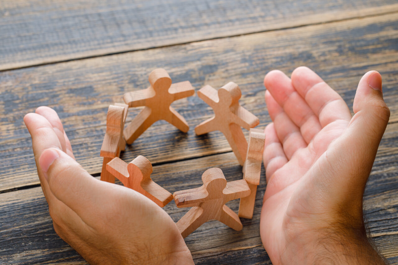 hands shielding wooden figures
