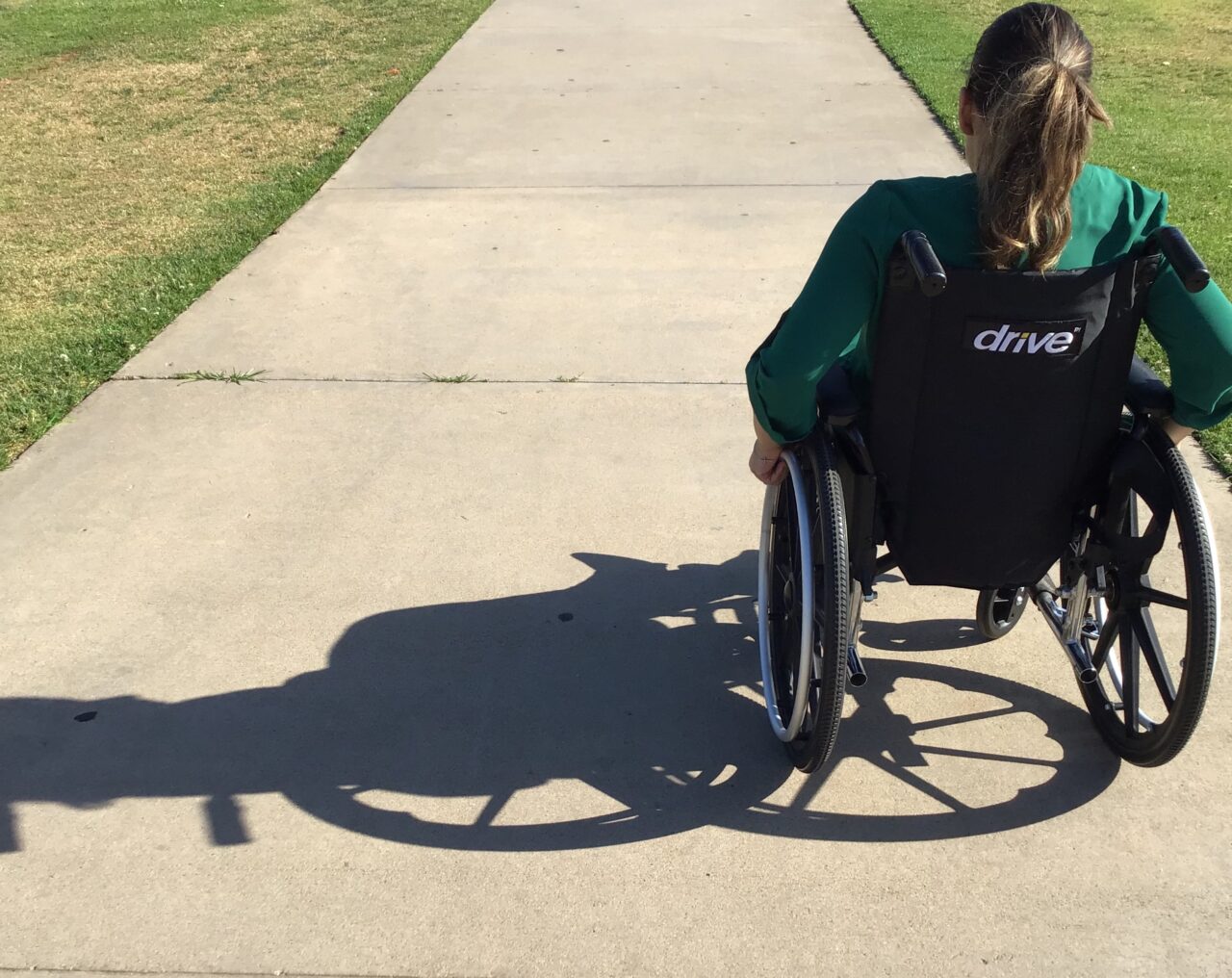 girl in wheelchair on sunny pavement